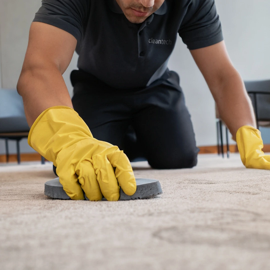 Cleantech employee wearing yellow gloves cleaning a commercial floor by hand for detailed janitorial service