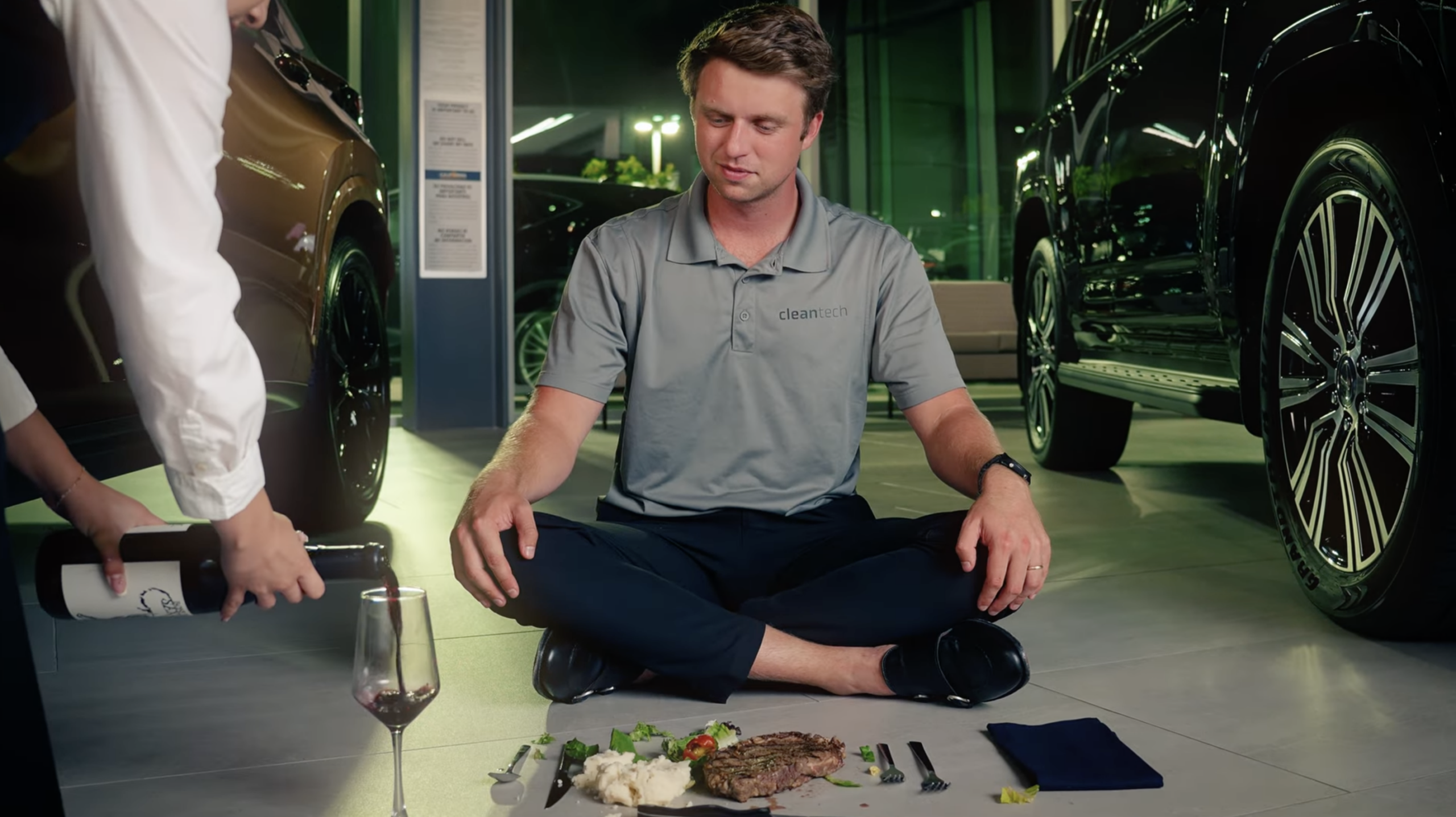 Cleantech CEO eating steak dinner off a freshly cleaned showroom floor inside a luxury car dealership to demonstrate cleaning quality
